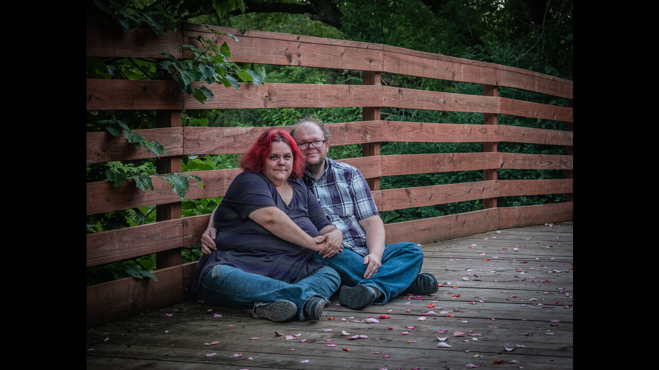 Danni and Alex sitting at side of bridge.