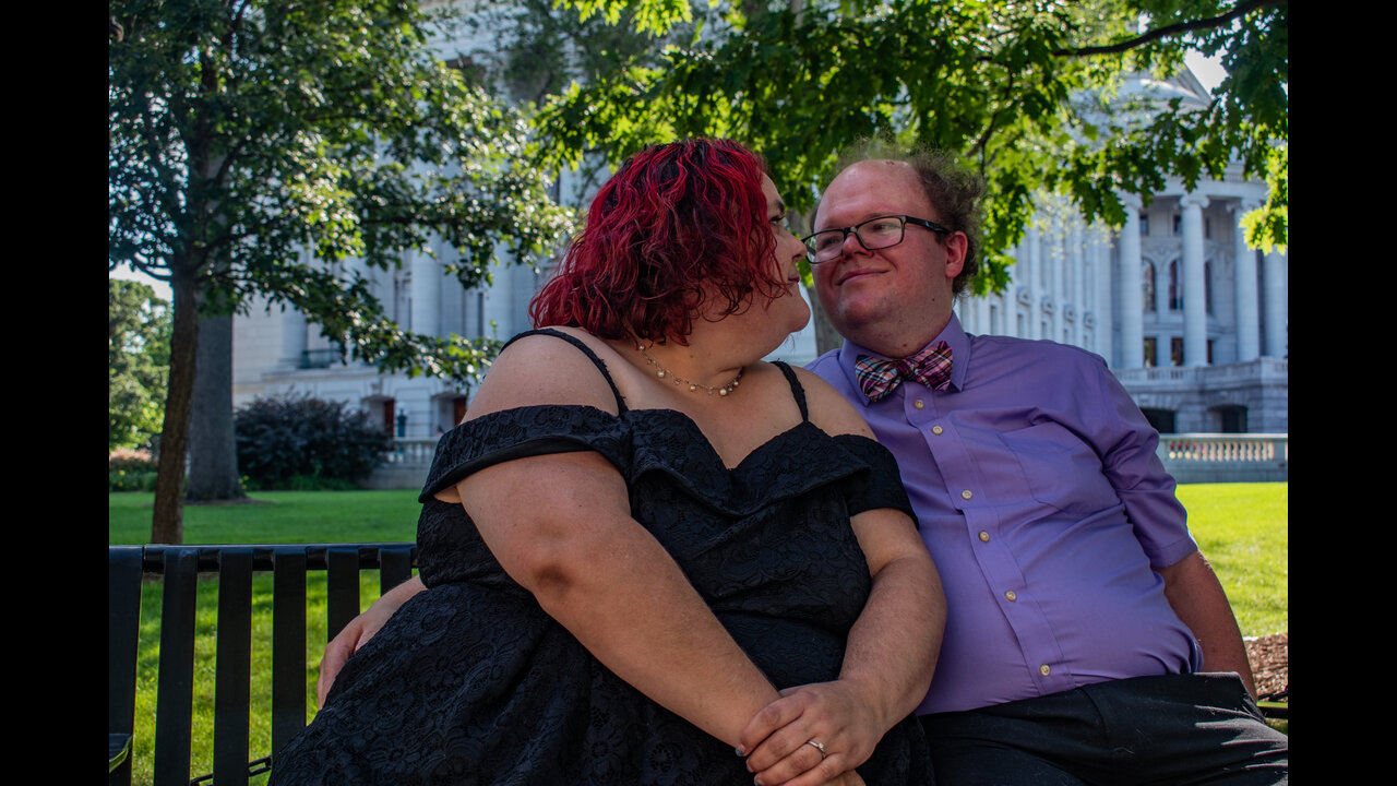 Danni and Alex looking into eachother's eyes on bench in front of the Wisconsin State Capitol.